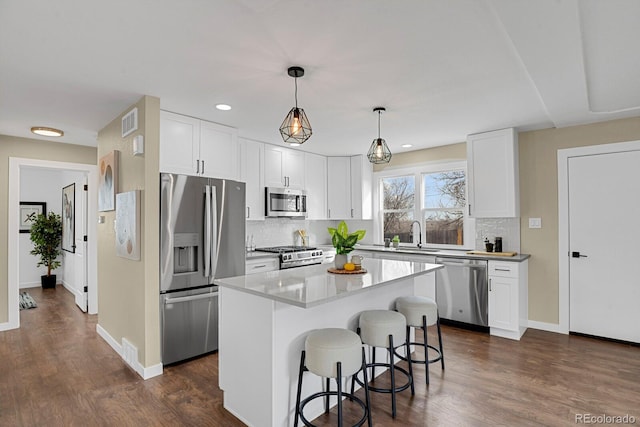 kitchen featuring white cabinetry, dark wood-type flooring, a kitchen island, and stainless steel appliances