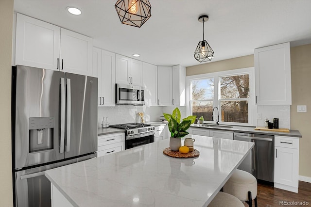 kitchen featuring sink, light stone counters, decorative light fixtures, white cabinets, and appliances with stainless steel finishes