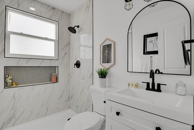 bathroom featuring a tile shower, vanity, and toilet