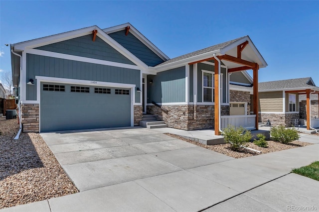 craftsman-style house featuring central air condition unit, an attached garage, a porch, and stone siding
