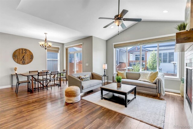 living area featuring a healthy amount of sunlight, baseboards, ceiling fan with notable chandelier, and wood finished floors