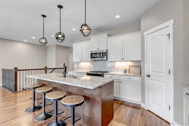 kitchen featuring light wood-style floors, recessed lighting, tasteful backsplash, a sink, and appliances with stainless steel finishes