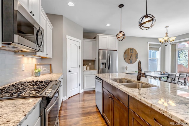 kitchen featuring a notable chandelier, a sink, stainless steel appliances, recessed lighting, and wood finished floors
