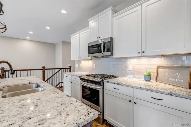 kitchen with tasteful backsplash, a sink, white cabinets, stainless steel appliances, and recessed lighting
