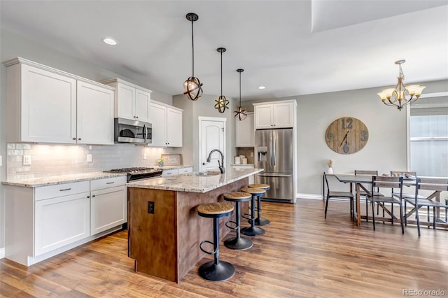 kitchen with backsplash, a kitchen bar, appliances with stainless steel finishes, a sink, and white cabinets
