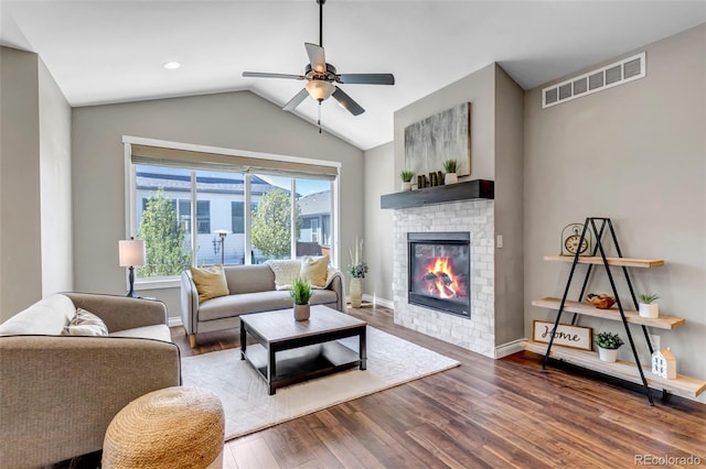 living room featuring visible vents, a brick fireplace, wood finished floors, a ceiling fan, and vaulted ceiling