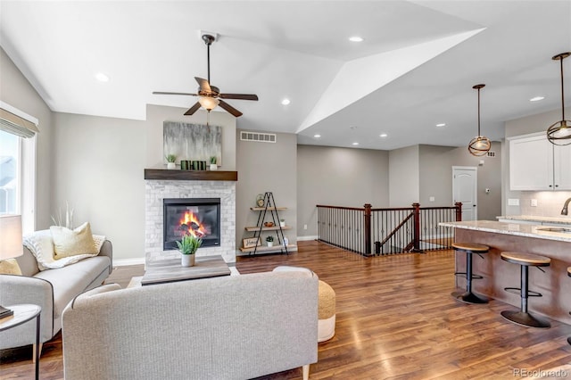 living area featuring a ceiling fan, visible vents, wood finished floors, and lofted ceiling