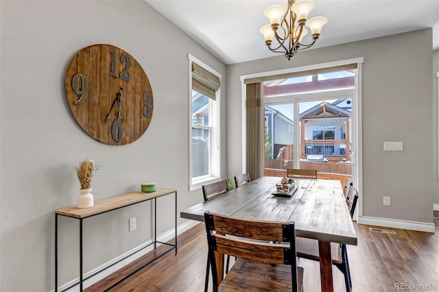 dining area featuring baseboards, visible vents, dark wood-type flooring, and a chandelier