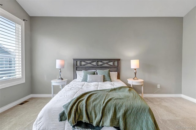 carpeted bedroom featuring baseboards, visible vents, and multiple windows
