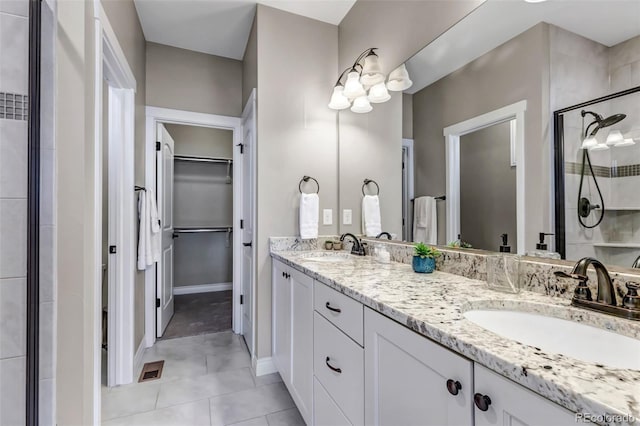 bathroom featuring double vanity, a sink, a spacious closet, and a shower stall