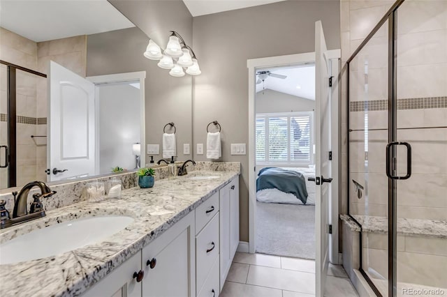 ensuite bathroom with a sink, tile patterned floors, a shower stall, and lofted ceiling