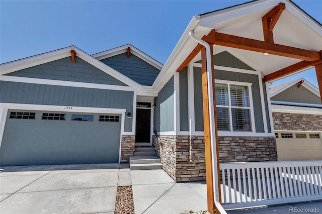 craftsman house with a garage, driveway, and stone siding