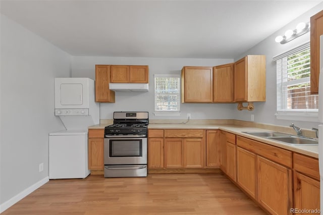 kitchen with light wood-type flooring, stacked washer and dryer, sink, and stainless steel gas stove