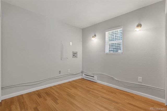 spare room with hardwood / wood-style floors and a baseboard heating unit