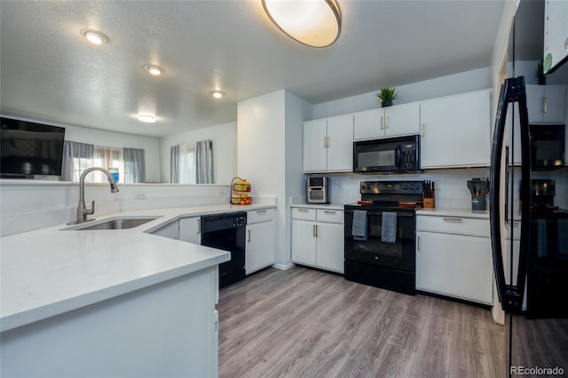 kitchen with white cabinetry, a textured ceiling, black appliances, light hardwood / wood-style floors, and sink