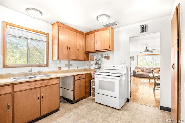 kitchen with white electric stove, light countertops, visible vents, a sink, and ceiling fan