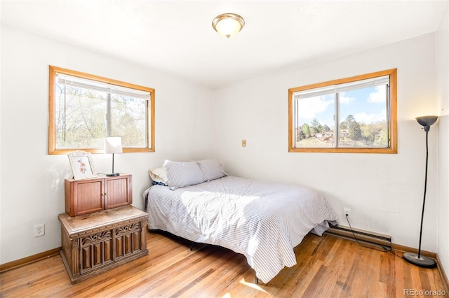bedroom featuring light wood-style floors, baseboards, and baseboard heating