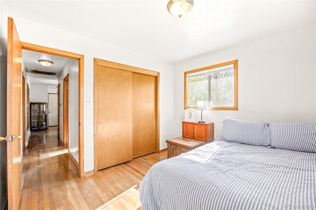 bedroom featuring a closet, light wood finished floors, and baseboards