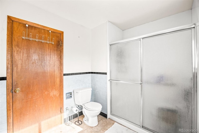 full bath with tile patterned floors, a wainscoted wall, a shower stall, and toilet