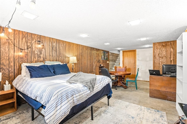 bedroom featuring concrete flooring, wood walls, and a textured ceiling