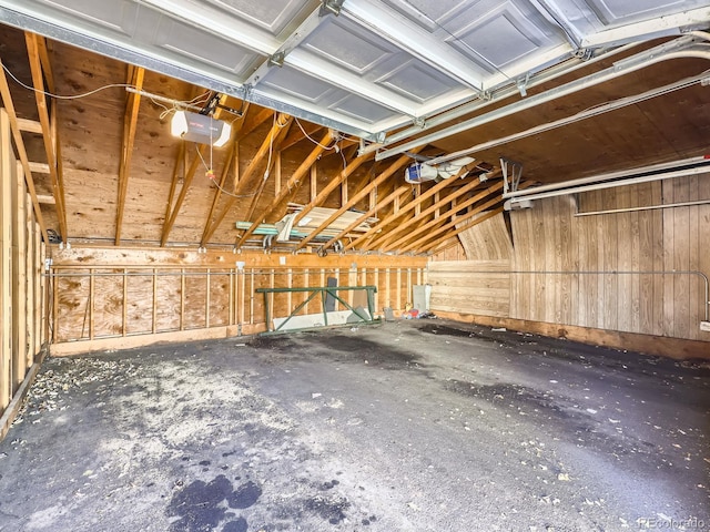 garage with a garage door opener and wooden walls