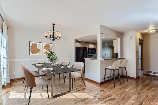 dining room with light wood finished floors, baseboards, visible vents, and a notable chandelier