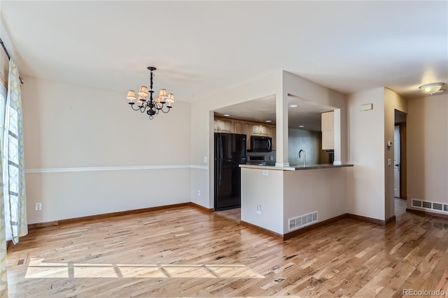 kitchen with light wood-style floors, freestanding refrigerator, visible vents, and a peninsula