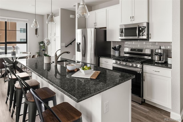 kitchen featuring white cabinetry, an island with sink, appliances with stainless steel finishes, and a breakfast bar