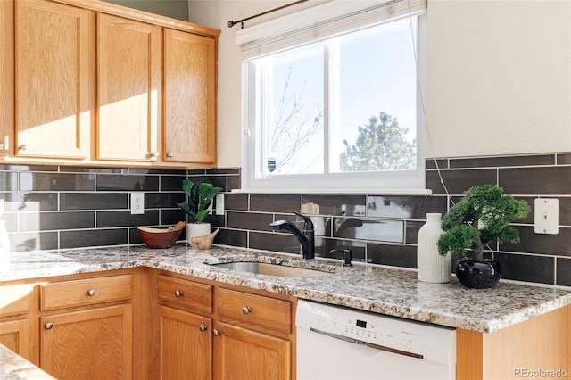 kitchen featuring backsplash, white dishwasher, light stone counters, and sink