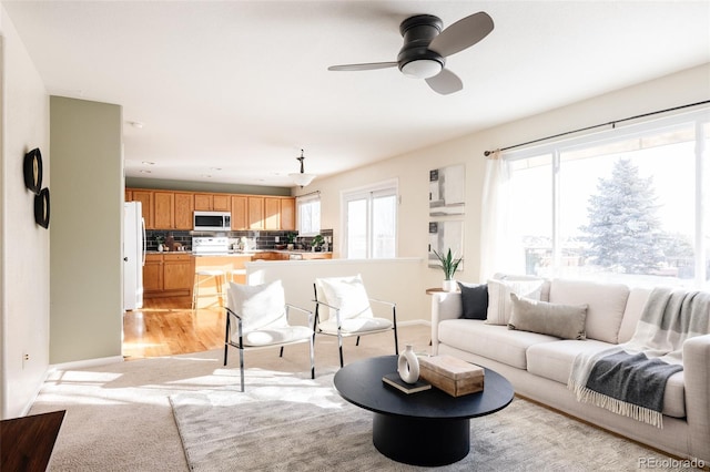 living room with light colored carpet, ceiling fan, and a healthy amount of sunlight