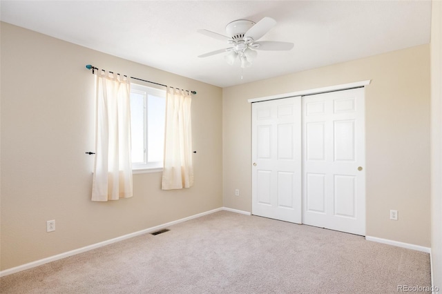 unfurnished bedroom featuring ceiling fan, light colored carpet, and a closet