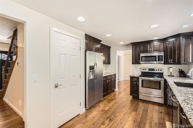 12454 Antelope Trl, Parker, CO 80138 - kitchen with stainless steel appliances, dark wood-type flooring, dark brown cabinetry, light stone counters, and recessed lighting