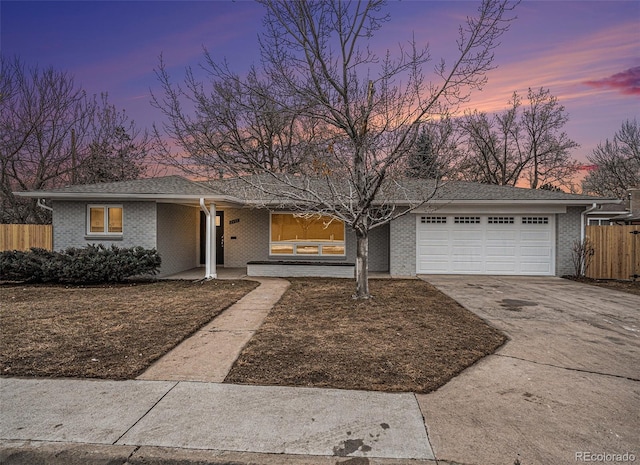 view of front of home with brick siding, driveway, an attached garage, and fence