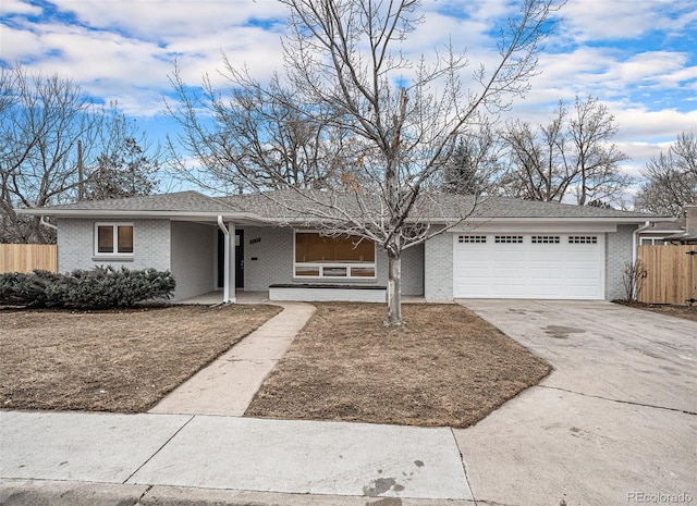 ranch-style house with a garage, brick siding, driveway, and fence