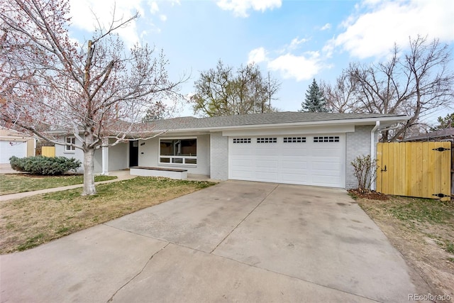 ranch-style house with fence, an attached garage, a front lawn, brick siding, and driveway