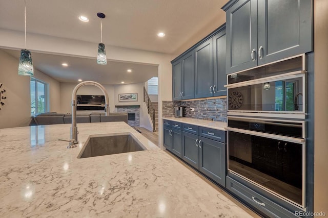 kitchen featuring sink, hanging light fixtures, decorative backsplash, light stone countertops, and double oven