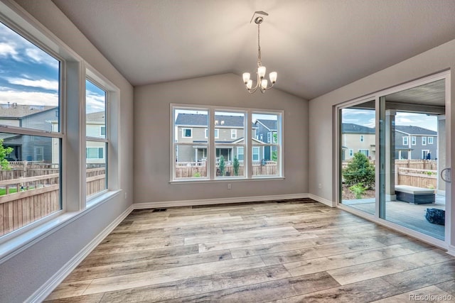 unfurnished dining area featuring light hardwood / wood-style flooring, plenty of natural light, a chandelier, and lofted ceiling