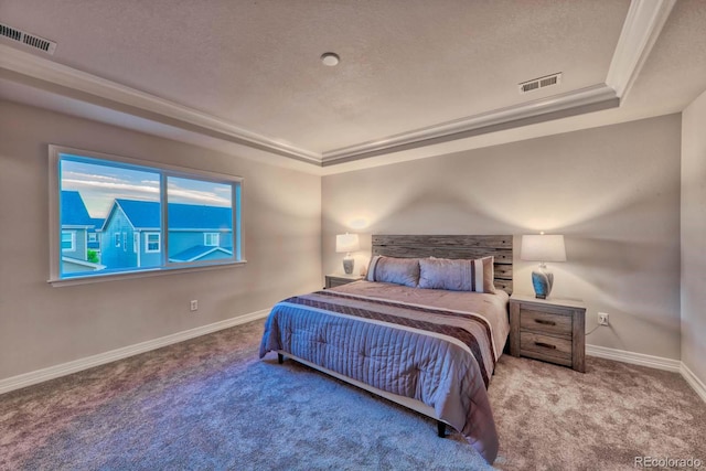 carpeted bedroom with a textured ceiling, a tray ceiling, and crown molding