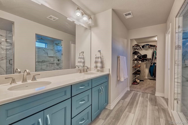 bathroom featuring wood-type flooring, vanity, a textured ceiling, and an enclosed shower