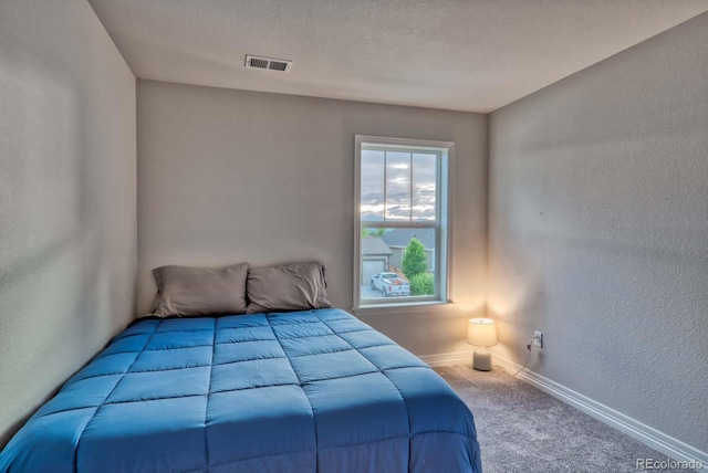 bedroom with carpet floors and a textured ceiling