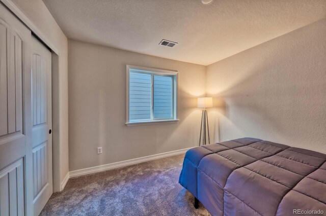 bedroom featuring carpet, a closet, and a textured ceiling