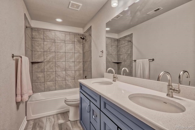 full bathroom featuring tiled shower / bath combo, vanity, and toilet