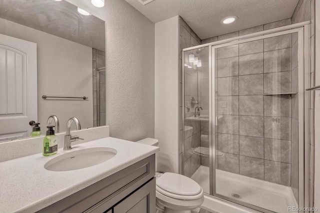 bathroom featuring vanity, a textured ceiling, toilet, and a shower with door