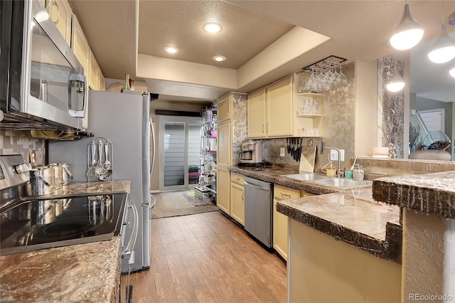 kitchen with light hardwood / wood-style floors, tasteful backsplash, pendant lighting, stainless steel appliances, and sink