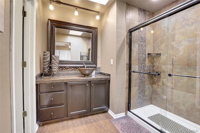 bathroom with a skylight, a shower with shower door, hardwood / wood-style flooring, and vanity