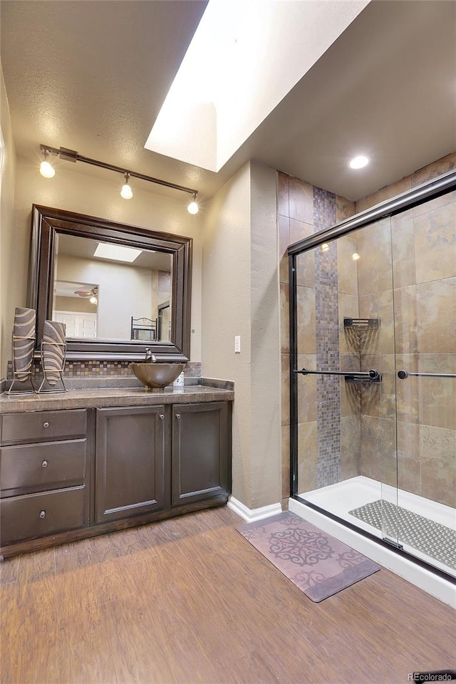 bathroom with vanity, hardwood / wood-style floors, a skylight, and an enclosed shower