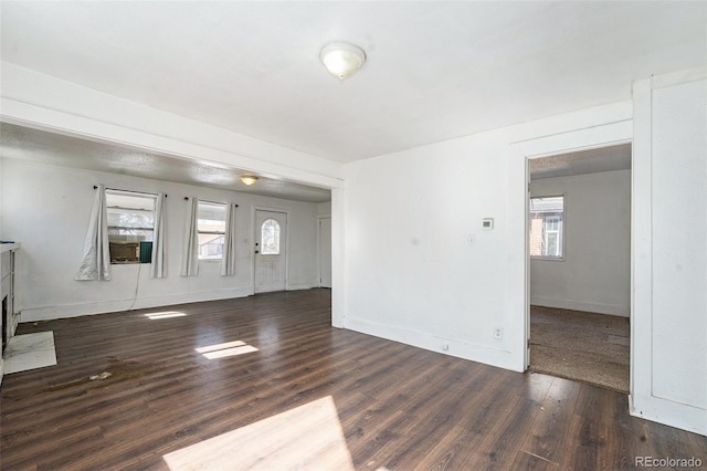 unfurnished living room with dark wood-style flooring, a fireplace with flush hearth, and baseboards