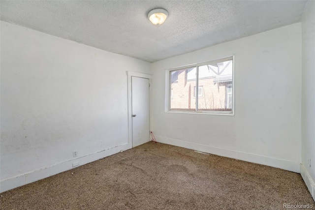 empty room with a textured ceiling, carpet floors, and baseboards