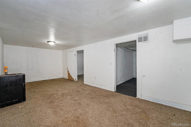 finished basement with carpet floors, visible vents, a textured ceiling, and baseboards