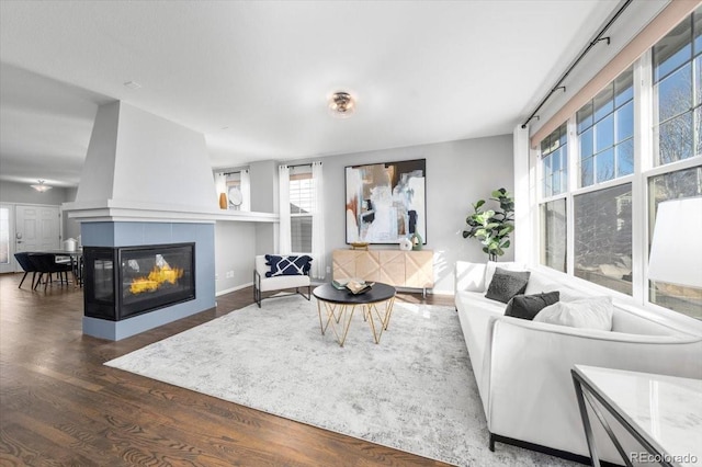 living room featuring a tiled fireplace, wood finished floors, and baseboards